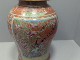 a large orange vase with a lid on a table