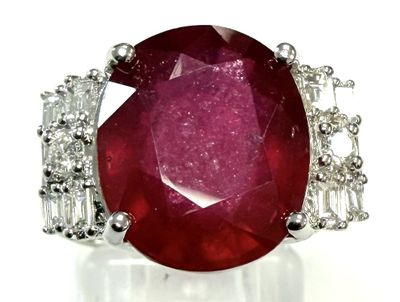 un gros plan d'une bague sertie d'un rubis et de diamants sur une surface blanche