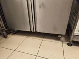 a stainless steel refrigerator in the middle of a tiled floor