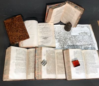 several open books sitting on top of a table next to a candle