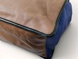 a brown and blue bag sitting on a white surface