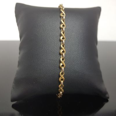 gros plan d'un bracelet en chaîne en or sur un oreiller