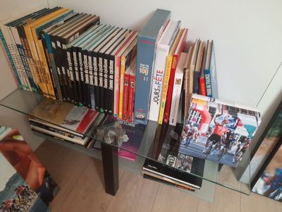 de nombreux livres posés sur une étagère en verre à côté d'un fauteuil