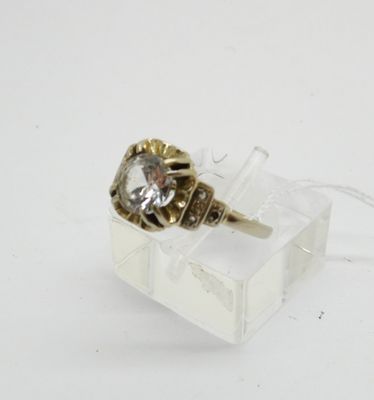 une bague sertie d'un diamant, posée sur une boîte transparente