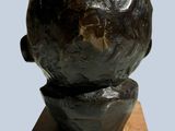 a black sculpture of a man ' s head on a wooden base