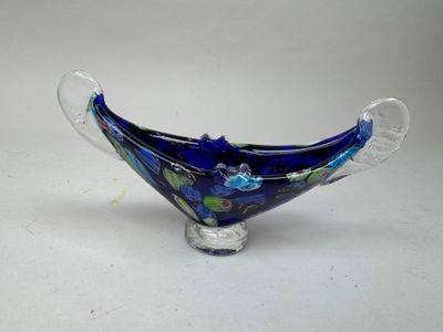 bol en verre bleu orné de fleurs et de feuilles, posé sur un fond blanc
