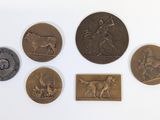 six médaillons en bronze de types et de tailles variés sur un fond blanc