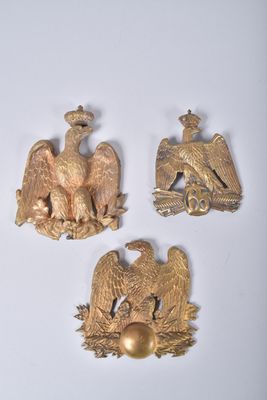trois broches en forme d'aigle doré sur un fond blanc, avec un œuf doré