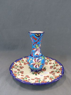 un vase bleu et rouge posé sur une assiette, sur une table