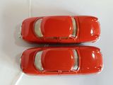 pair of red toy cars sitting on top of a white surface