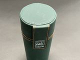 a green cup sitting on a table with a leather lid