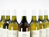 six bottles of white wine lined up in a row on a table