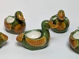 six ceramic ducks are lined up in a row on a white surface