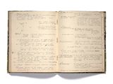 un livre ouvert, sur lequel figurent des inscriptions, posé sur une surface blanche