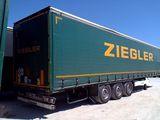 a green semi truck that is parked next to a building