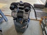 a small air compressor sitting on the floor in a garage