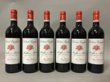 six bottles of red wine are lined up on a table