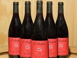 six bouteilles de vin rouge sont alignées sur un tonneau