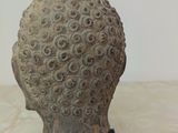 sculpture of a head on a black stand on a marble surface