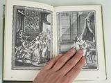 someone is holding a book open to a picture of a man in a room