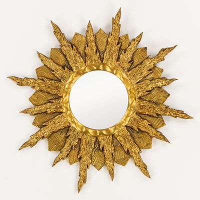 un miroir en forme d'étoile dorée accroché à un mur blanc