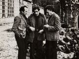 photographie en noir et blanc de trois hommes debout devant un immeuble