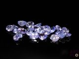 a close up of a bunch of purple sapphires on a black surface