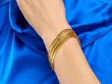 une femme portant une chemise bleue et des bracelets dorés