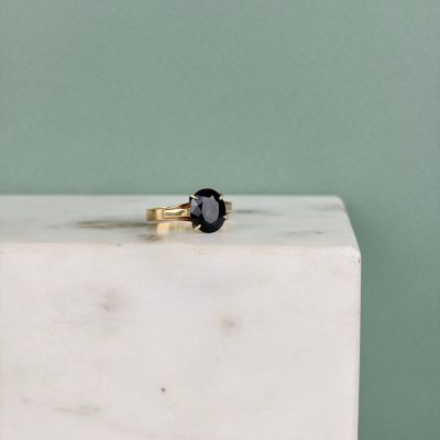 une bague en diamant noir posée sur un bloc de marbre blanc