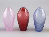quatre vases de couleurs différentes posés côte à côte sur une surface blanche