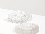 un objet en verre posé sur une surface blanche, sur laquelle se projette son ombre