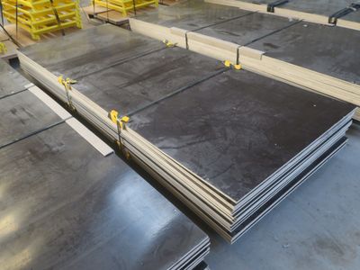 Plusieurs pièces d'acier sont empilées sur des palettes dans un entrepôt