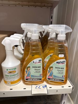 Plusieurs bouteilles de produits d'entretien sont posées sur une étagère dans une salle de bains.