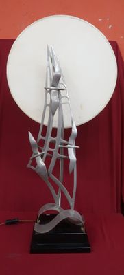 une sculpture métallique représentant un voilier, posée sur une assiette blanche
