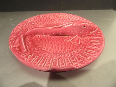 une assiette rose avec un poisson dessiné dessus, posée sur une table