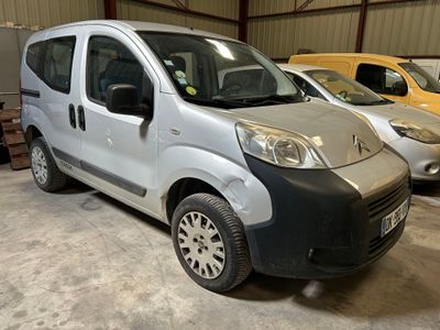 une petite camionnette argentée garée dans un garage avec d'autres voitures