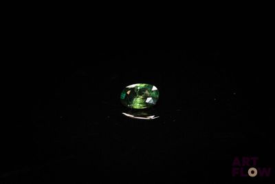 a close up of a green tourmaline stone on a black surface