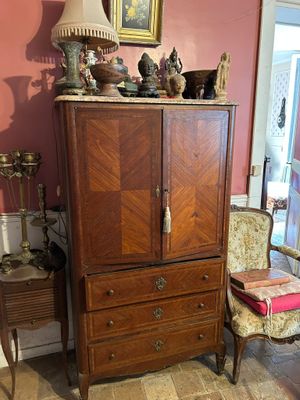 une armoire et une chaise dans une pièce où est accroché un tableau au mur