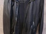 une veste en cuir noir suspendue à un cintre accroché au mur