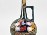 un vase vert orné d'un motif sur fond blanc
