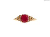 gros plan d'une bague avec une pierre rouge entourée de diamants