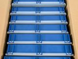 an open cardboard box with six rows of blue trays in it
