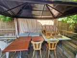 a table and chairs on a wooden deck under a canopy