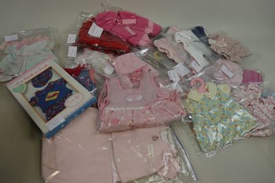une pile de vêtements pour bébés et d'autres objets posés sur une table