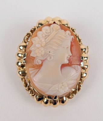 un gros plan sur le visage d'une femme dans une broche en or