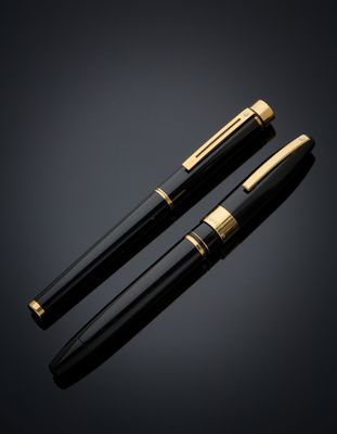 a pair of black and gold fountain pens on a black background