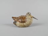 une petite figurine représentant un oiseau posé sur une surface blanche