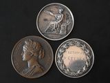 three silver coins with a woman on them on a black surface