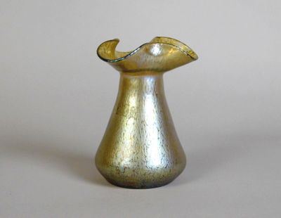 a gold vase with a curved handle on a white surface