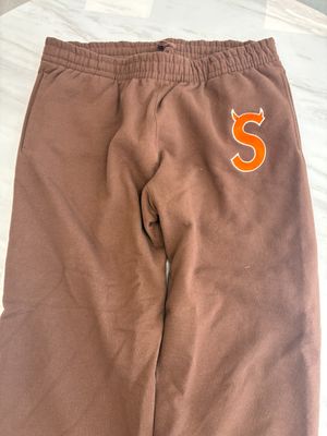 brown sweat pants with orange s on the side of the pants